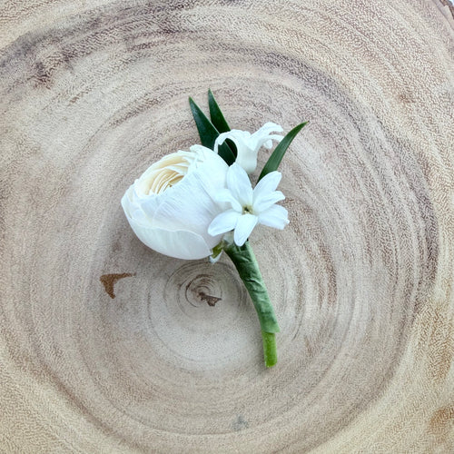 White flower boutonniere on a wooden surface