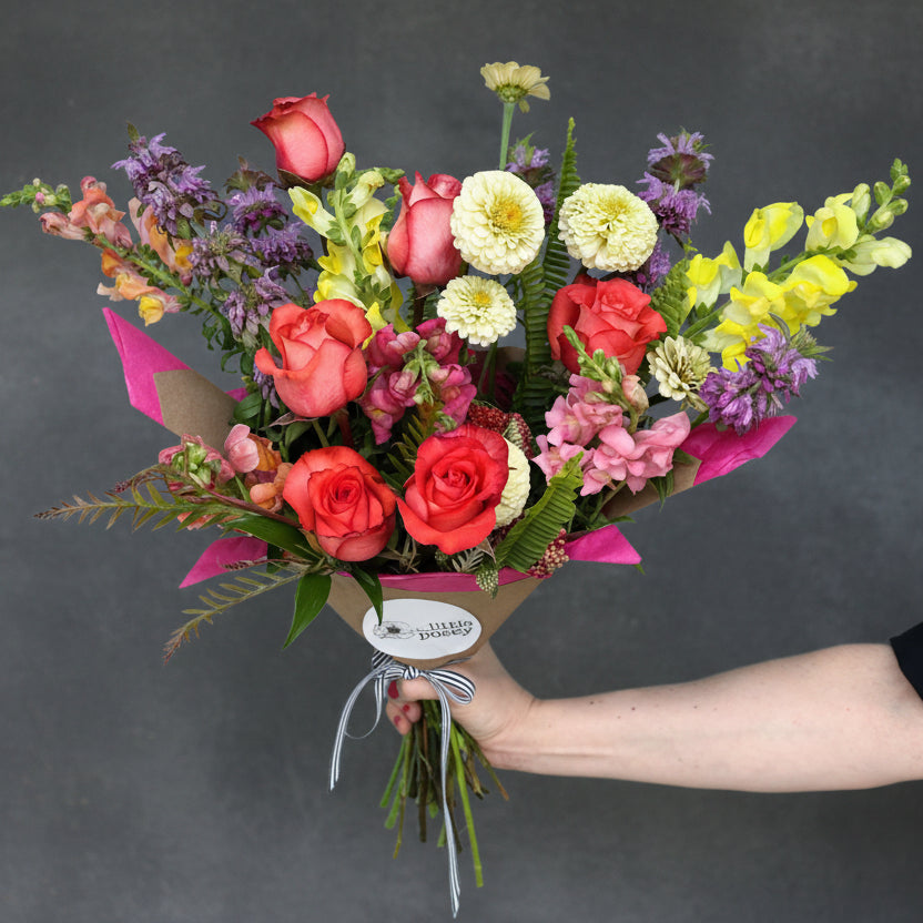 Bouquet of colorful flowers held by a person against a blue background for Delivery in austin, tx today