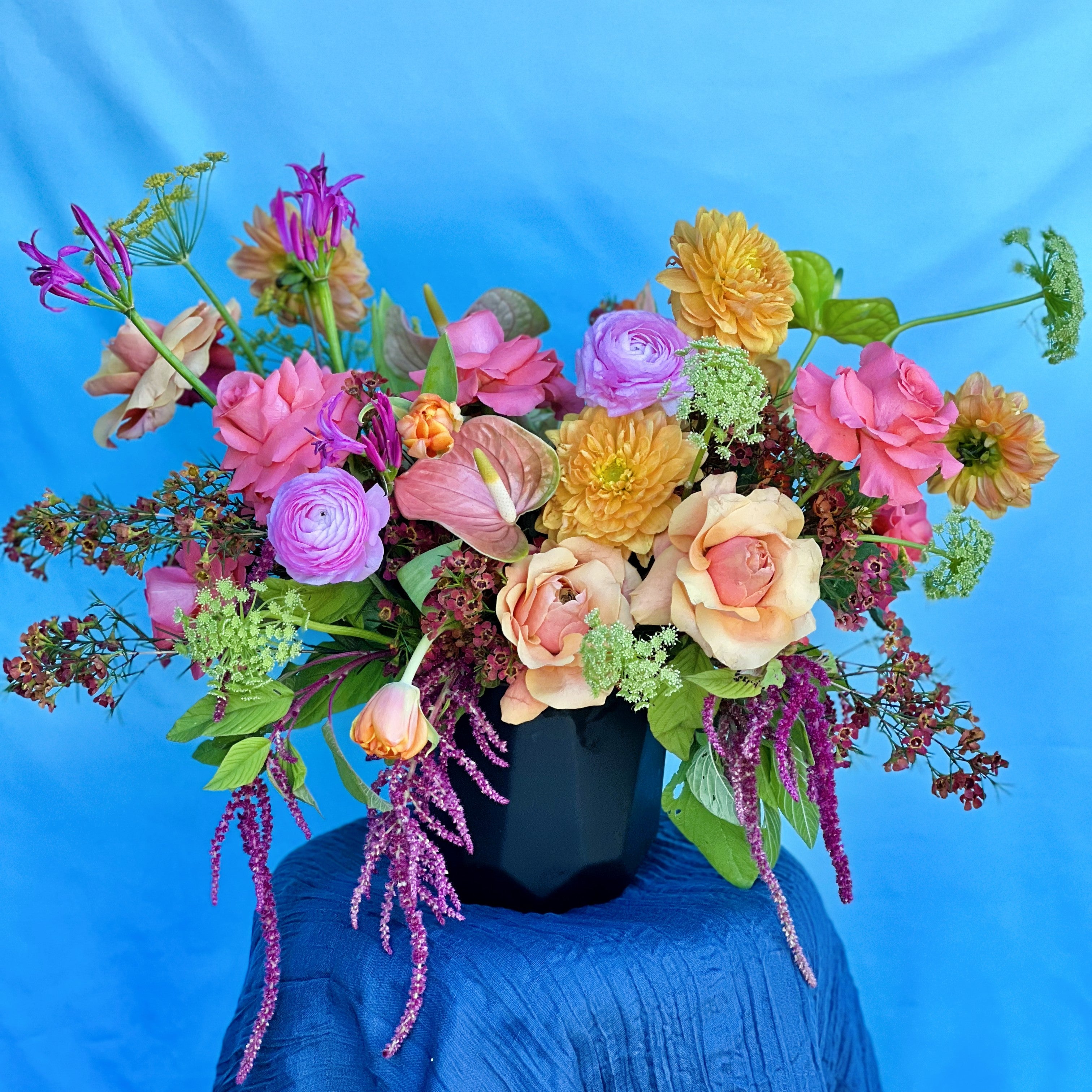 Colorful flower arrangement on a blue surface with a blue background delivered in Tarrytown Austin TX