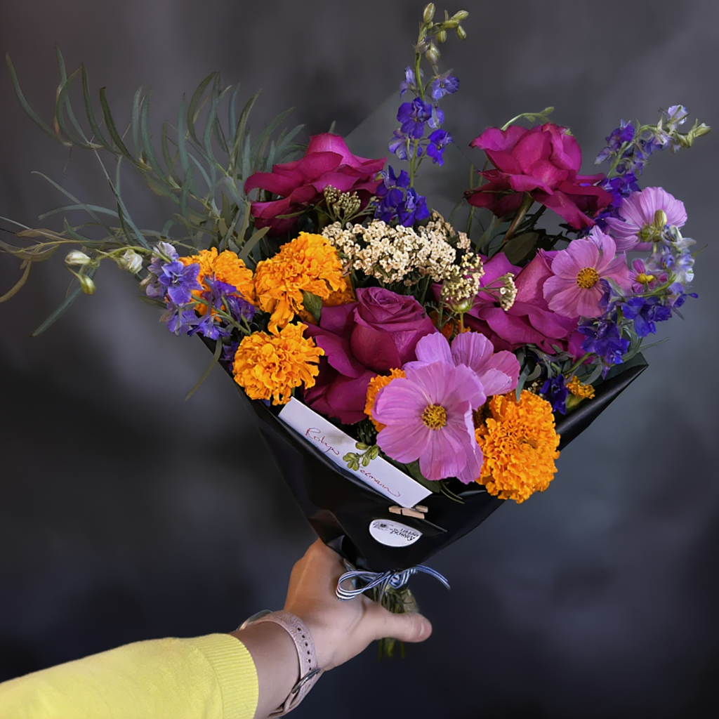 Bouquet of colorful flowers held by a person against a dark background in Austin texas for delivery