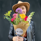 Person holding a bouquet of flowers with 'Little Posey' branding against a dark background