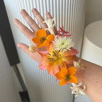 Floral wired corsage with orange and pink flowers on a neutral background at Posey Floral in Austin TX